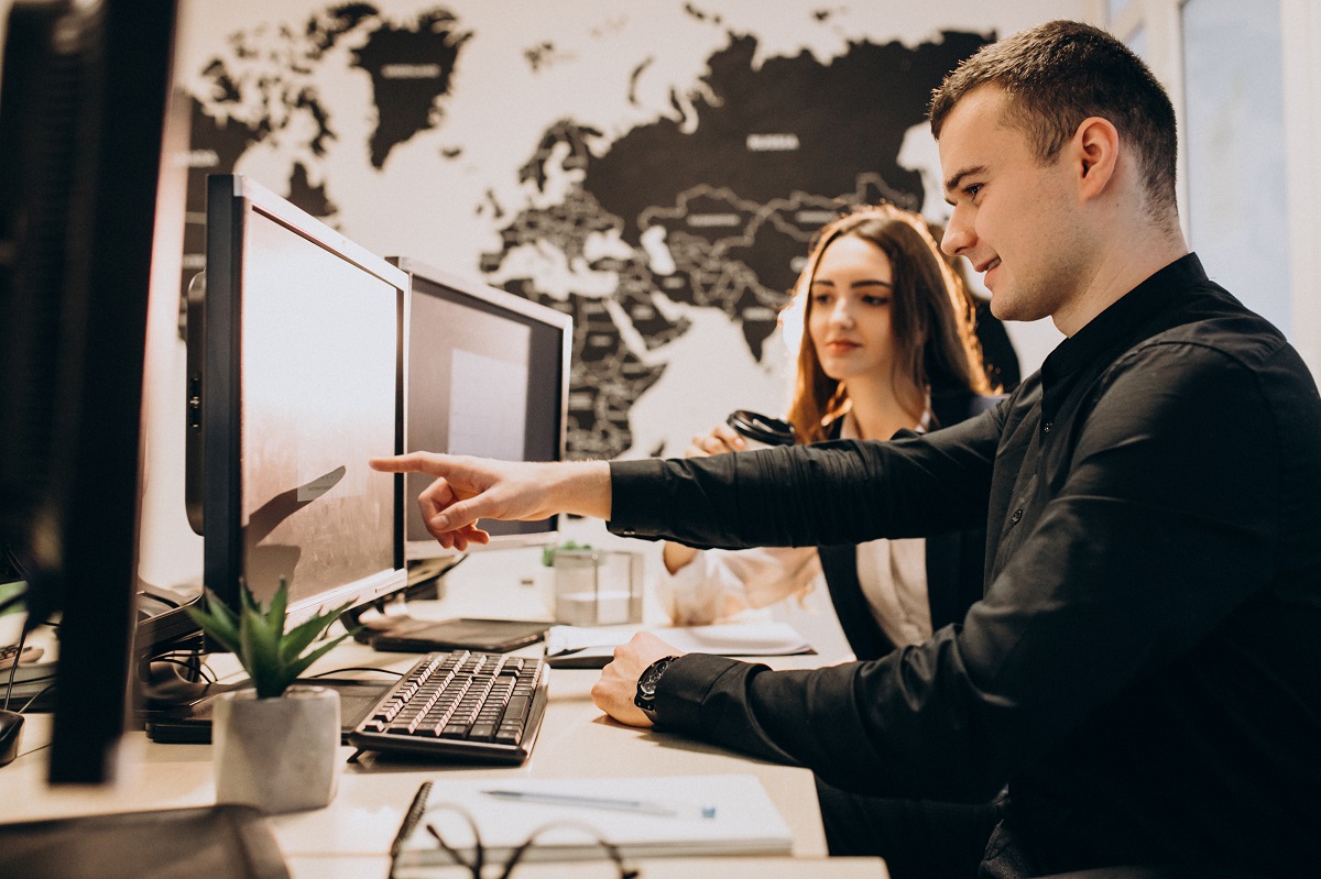 Man with a woman in office attire pointing to computer monitor