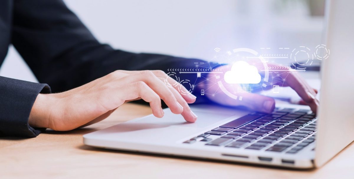 Professional hand on laptop with glowing cloud icon